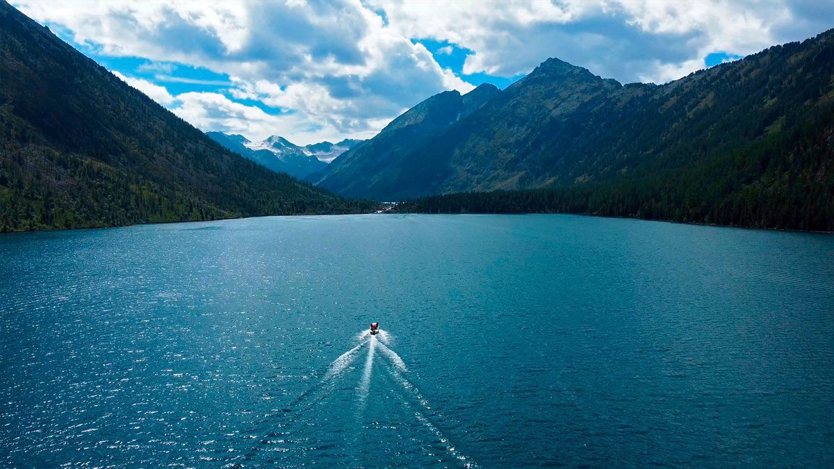 Вид с дрона на Нижнее Мультинское озеро в Горном Алтае и моторную лодку на воде